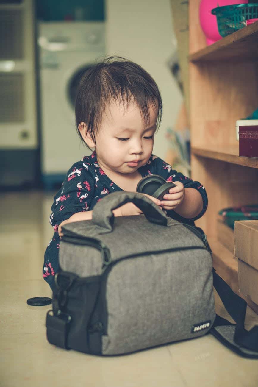 baby girl playing with a camera bag on an apartment floor