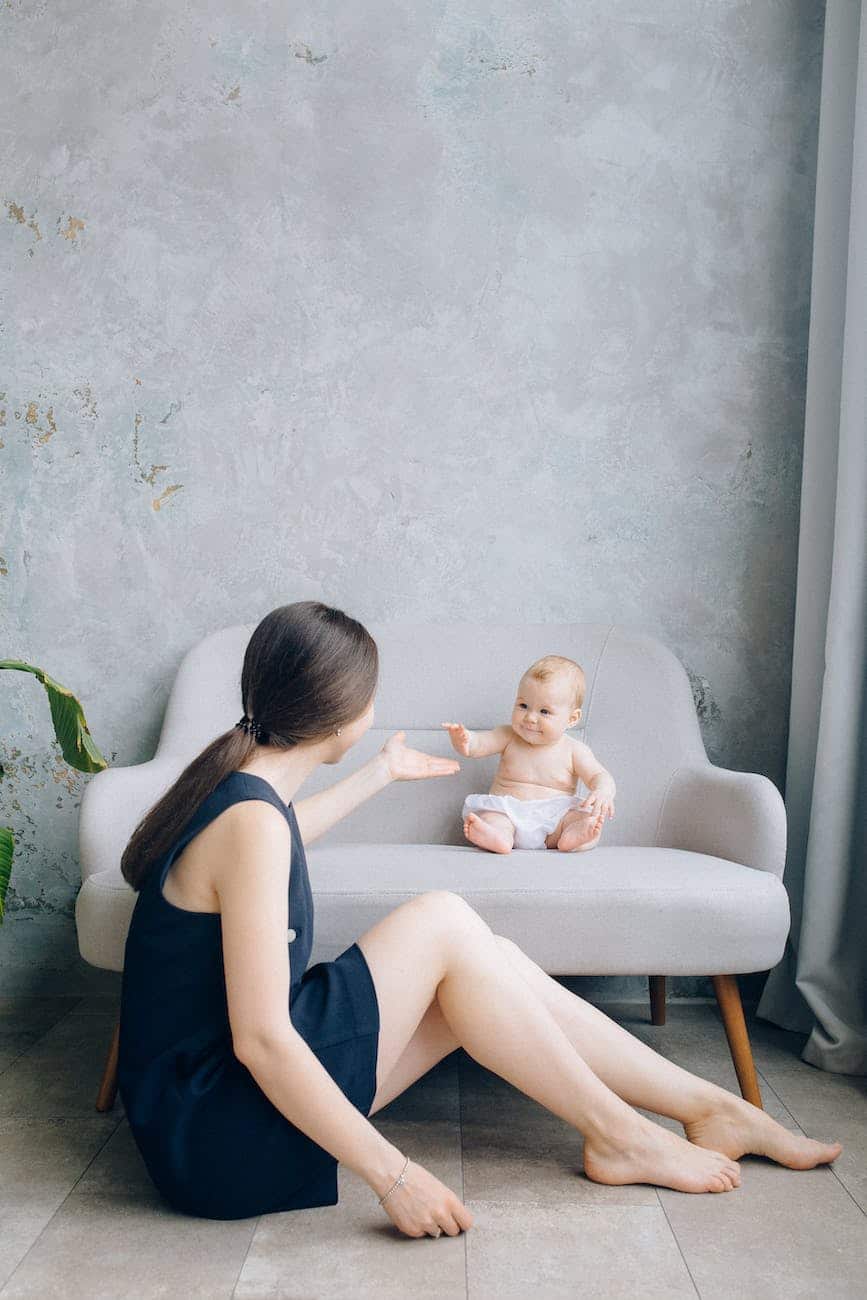 baby sitting on a sofa chair and a woman sitting on the floor