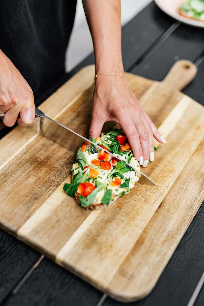 close up of woman cutting food on board