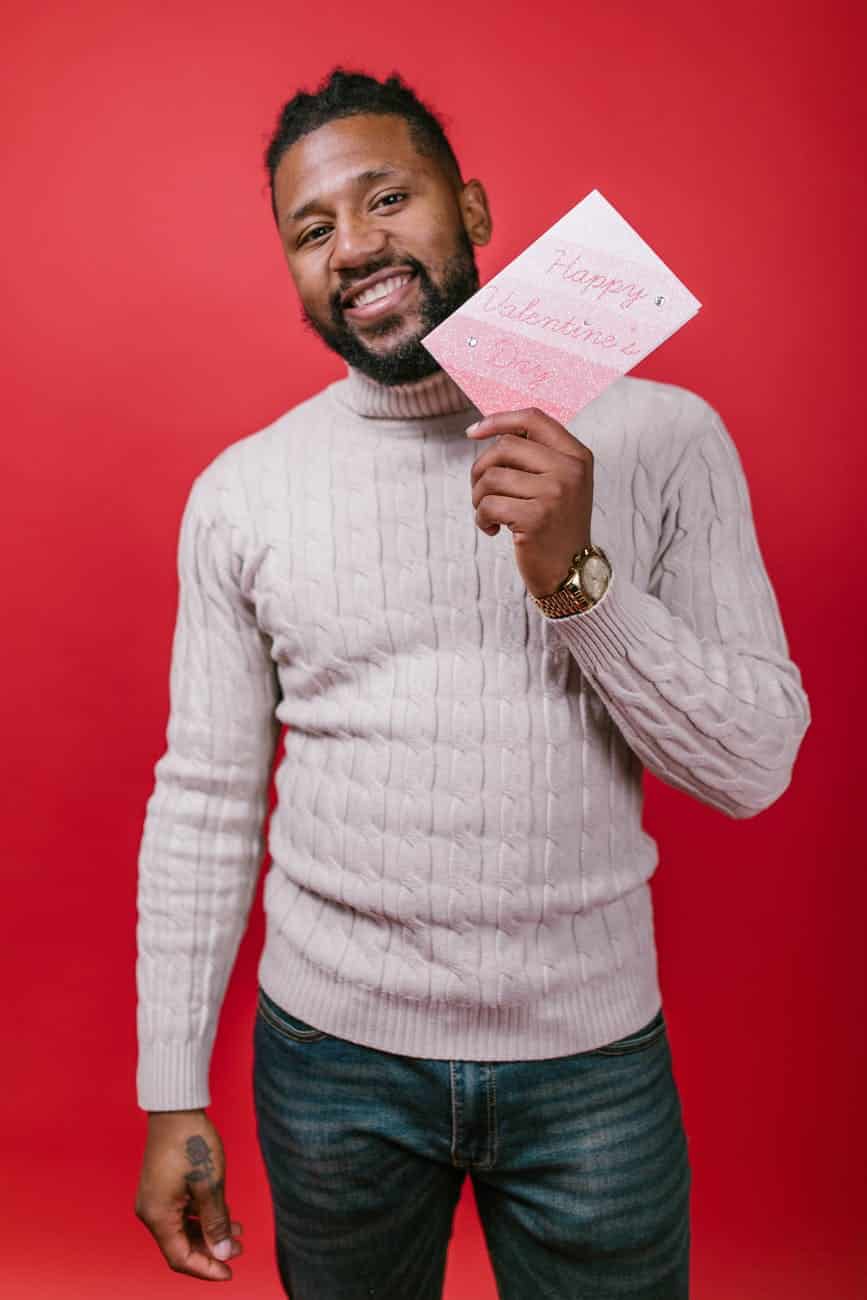 man in white sweater holding a valentine s day card