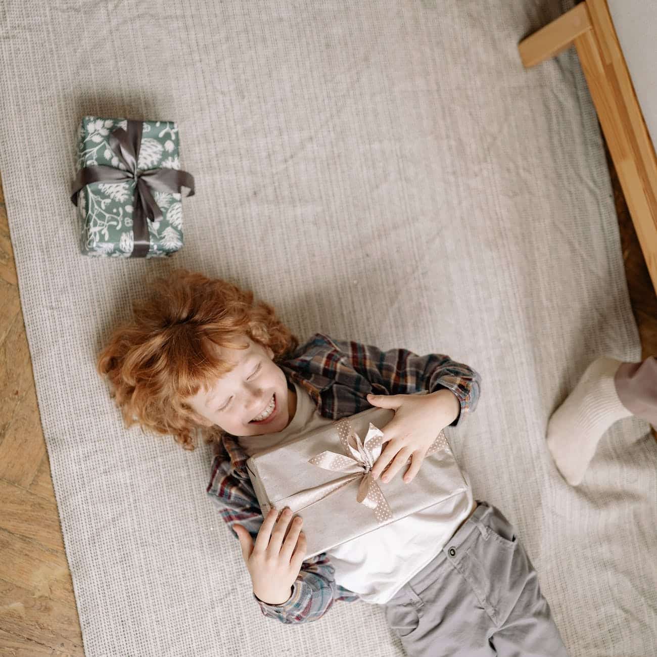 a happy boy holding a present while lying down on a floor