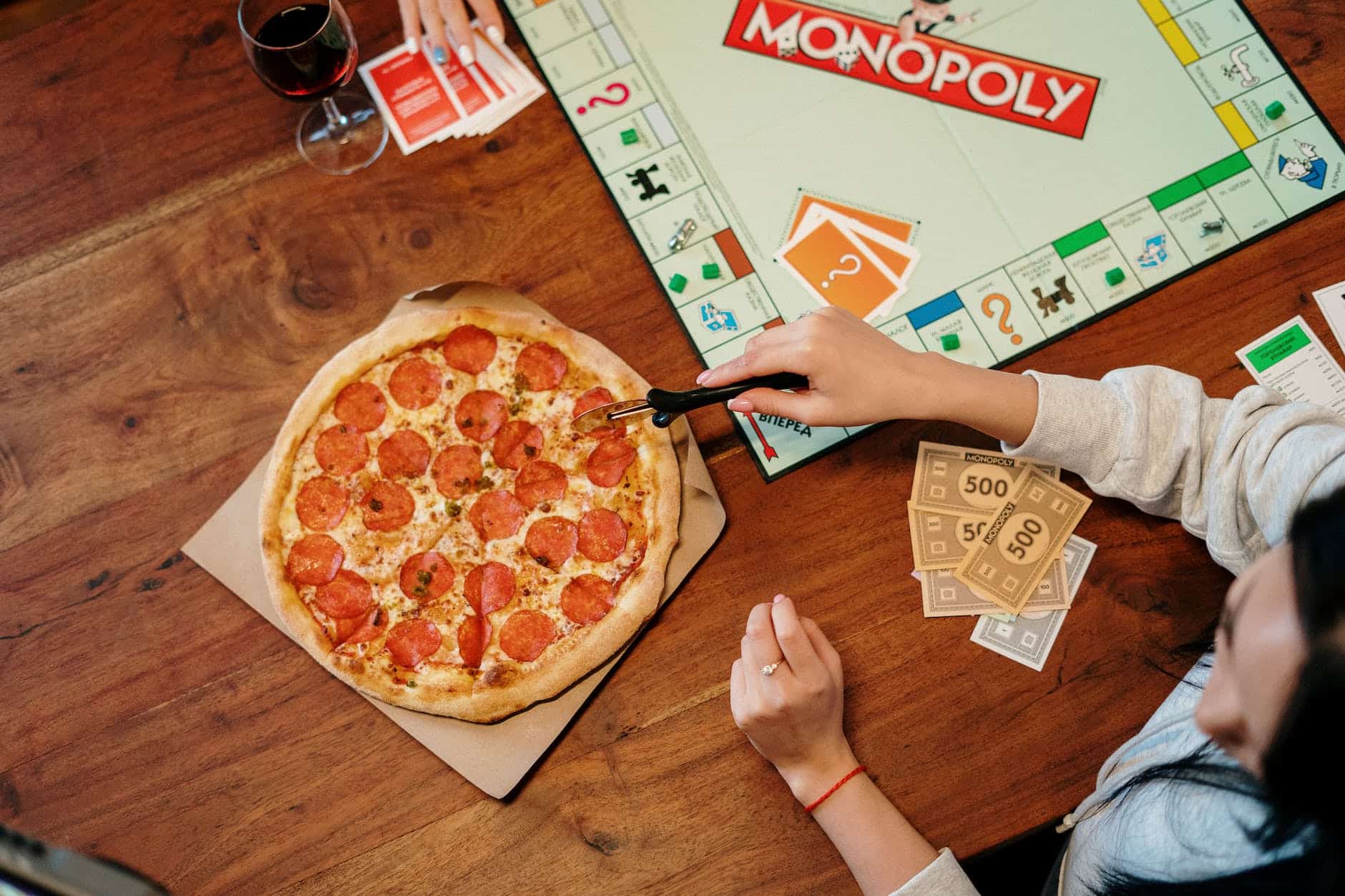 pizza and monopoly board game on wooden surface