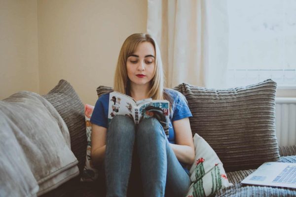 woman sitting on couch while reading a book