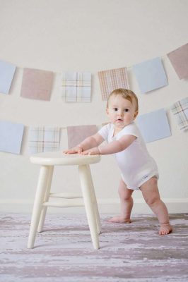 baby holding white wooden stool