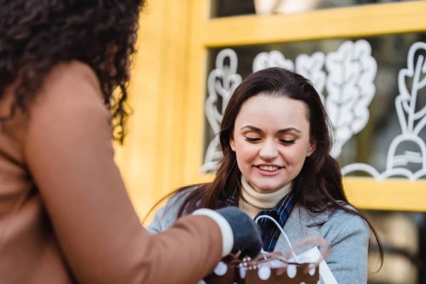 women at table checking gift packages in street near building